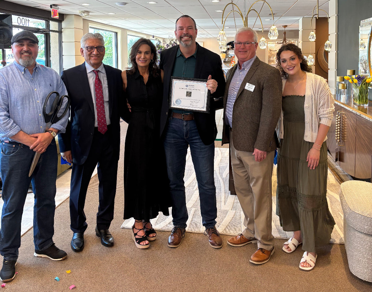 Group of people posing for a photo in an office setting with a man holding a certificate.